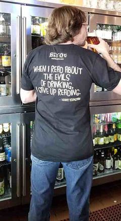 Person drinking beer wearing tee shirt saying When I read about the evils of drinking I gave up reading